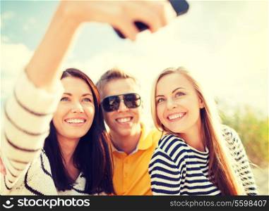 summer, holidays, technology, vacation and happiness concept - group of friends taking picture with smartphone camera