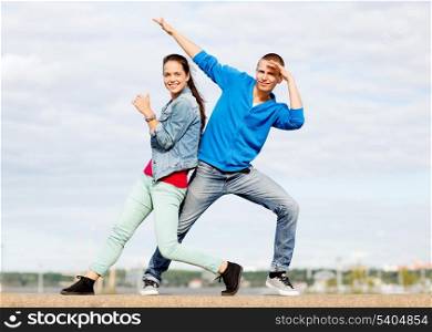summer holidays, teenage and dancing concept - couple of teenagers dancing outside