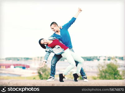 summer holidays, teenage and dancing concept - couple of teenagers dancing outside