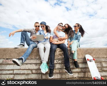 summer holidays, teenage and technology concept - group of teenagers looking at tablet pc