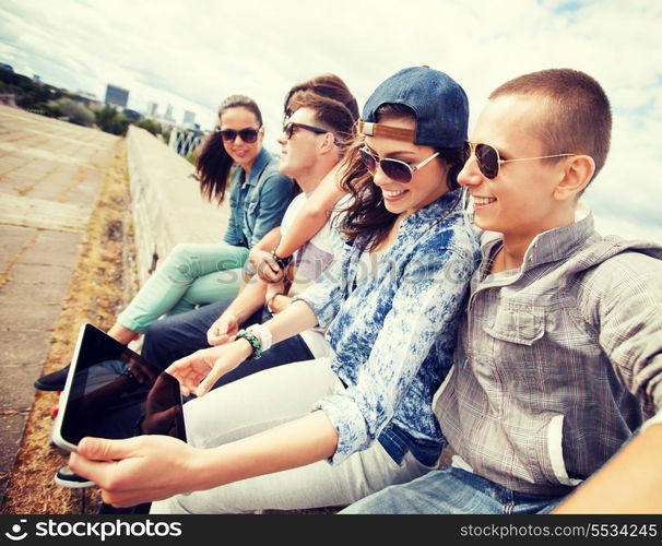 summer holidays, teenage and technology concept - group of teenagers looking at tablet pc