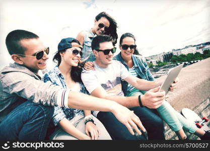 summer holidays, teenage and technology concept - group of teenagers looking at tablet pc