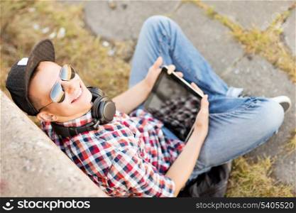 summer holidays, teenage and technology concept - teenager with headphones and tablet pc outside