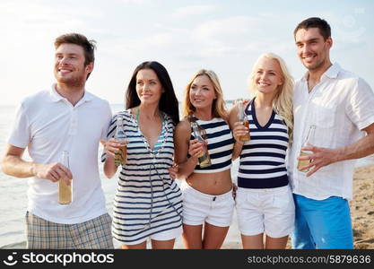 summer, holidays, tourism, drinks and people concept - group of smiling friends with bottles drinking beer or cider on beach