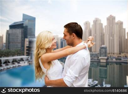 summer holidays, tourism, vacation, travel and dating concept - happy couple hugging over dubai city waterfront background
