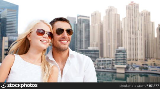 summer holidays, tourism, vacation, travel and dating concept - happy couple in shades over dubai city background