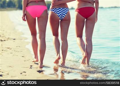 summer holidays, travel, body care and people concept - close up of happy young women walking and hugging on beach from back
