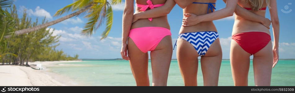 summer holidays, travel, body care and people concept - close up of happy young women walking and hugging from back over beach background