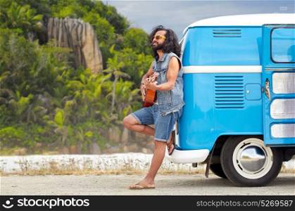 summer holidays, travel, music and people concept - young hippie man playing guitar and singing at minivan car over tropical island beach background. hippie man playing guitar at minivan car on island