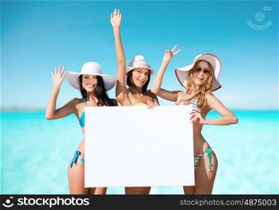 summer holidays, travel, people, advertisement and vacation concept - happy young women in bikinis holding white board over exotic tropical beach background