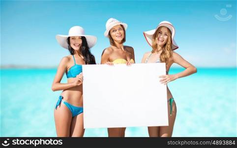 summer holidays, travel, people, advertisement and vacation concept - happy young women in bikinis holding white board over sea beach background