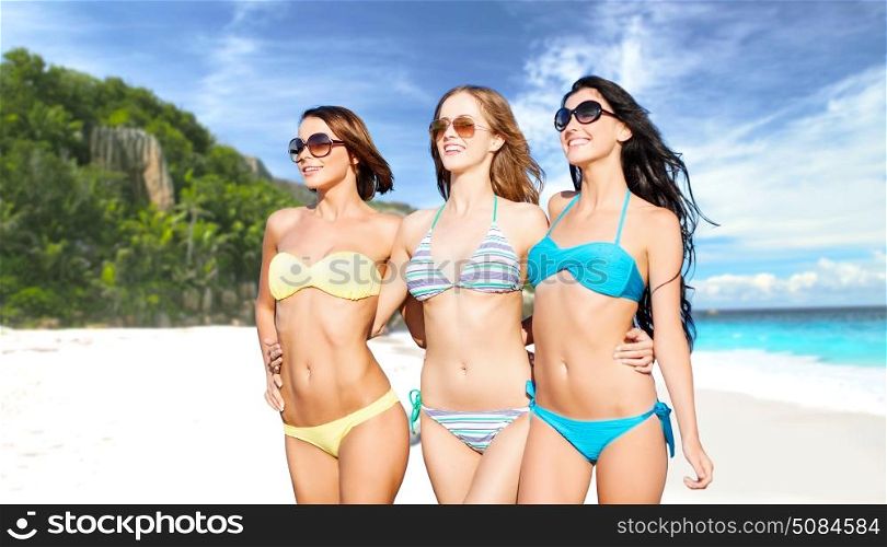 summer holidays, travel, people and vacation concept - happy smiling young women in bikinis and shades over exotic tropical beach background. happy young women in bikinis on summer beach. happy young women in bikinis on summer beach