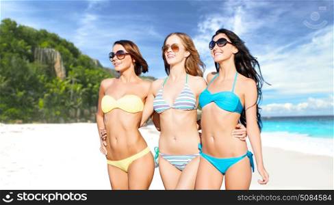 summer holidays, travel, people and vacation concept - happy smiling young women in bikinis and shades over exotic tropical beach background. happy young women in bikinis on summer beach. happy young women in bikinis on summer beach