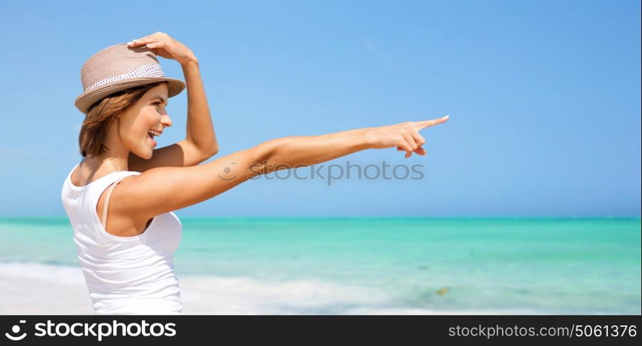 summer holidays, travel, people and vacation concept - happy young woman in hat pointing finger over exotic tropical beach background. happy young woman in hat on summer beach