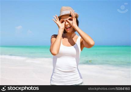 summer holidays, travel, people and vacation concept - happy young woman in hat making finger glasses over exotic tropical beach background. happy young woman in hat on summer beach. happy young woman in hat on summer beach