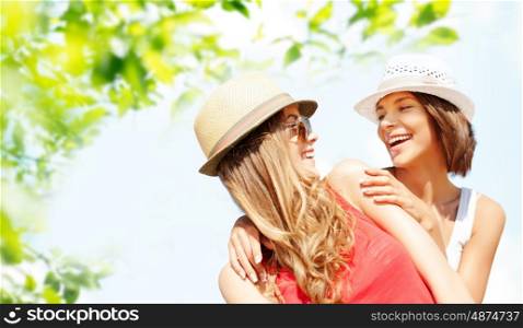summer holidays, travel, people and vacation concept - happy young women in hats over green foliage background