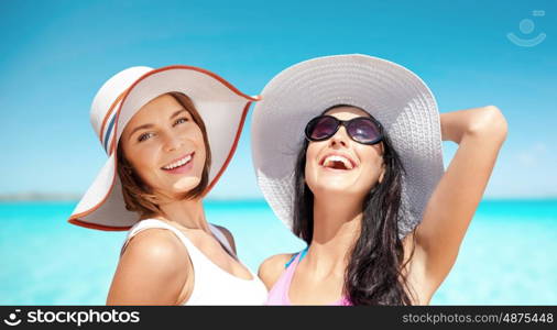 summer holidays, travel, people and vacation concept - happy young women in hats over over exotic tropical beach background