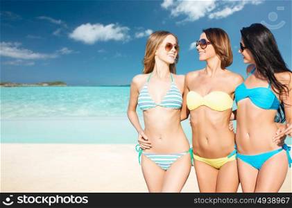 summer holidays, travel, people and vacation concept - happy young women in bikinis and shades over exotic tropical beach background. happy young women in bikinis on summer beach