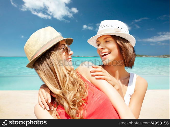 summer holidays, travel, people and vacation concept - happy young women in hats over exotic tropical beach background. happy young women in hats on summer beach