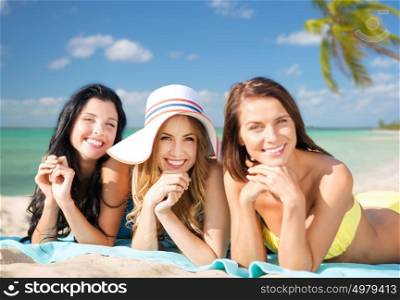 summer holidays, travel, people and vacation concept - happy young women in bikinis sunbathing over exotic tropical beach with palm trees and sea shore background. happy young women in bikinis on summer beach