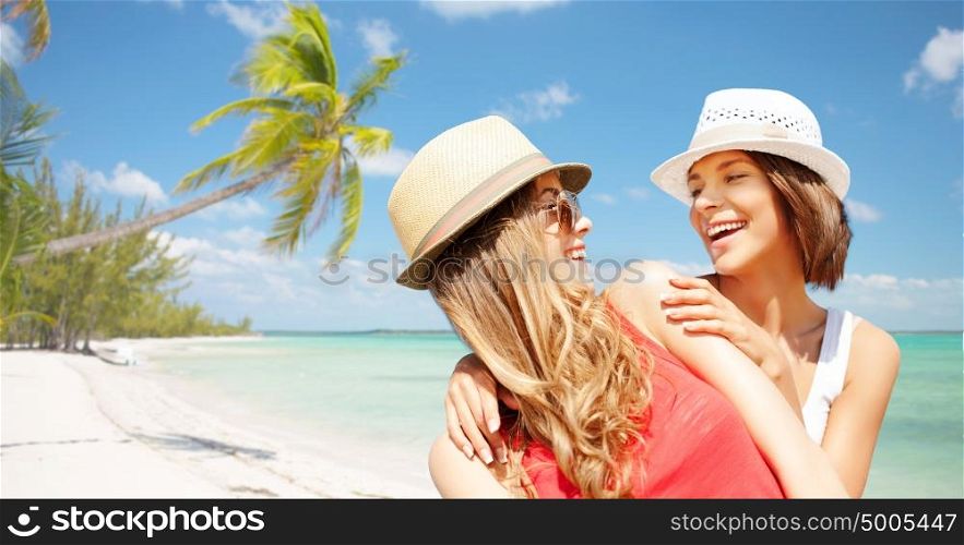 summer holidays, travel, people and vacation concept - happy young women in hats over exotic tropical beach with palm trees and sea shore background. happy young women in hats on summer beach