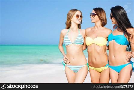 summer holidays, travel, people and vacation concept - happy young women in bikinis and shades over exotic tropical beach background. happy young women in bikinis on summer beach