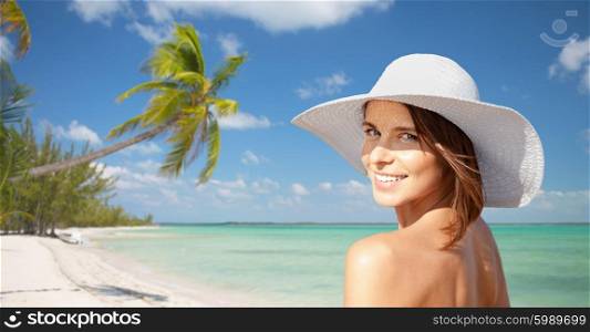 summer holidays, travel, people, tourism and vacation concept - happy young woman in sunhat over beach with palm trees background