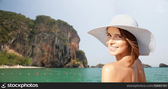 summer holidays, travel, people, tourism and vacation concept - happy young woman in sunhat over bali beach with cliff and sea background