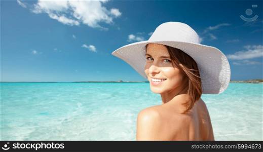 summer holidays, travel, people, tourism and vacation concept - happy young woman in sunhat over beach background