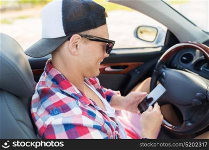 summer holidays, travel, road trip and people concept - happy young man with smartphone in convertible car. happy young man with smartphone in convertible car