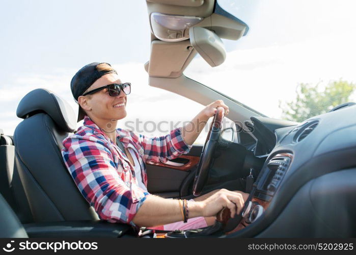 summer holidays, travel, road trip and people concept - happy young man driving convertible car with manual transmission. happy young man driving convertible car