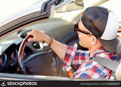 summer holidays, travel, road trip and people concept - happy young man in sunglasses and cap driving convertible car. happy young man in shades driving convertible car