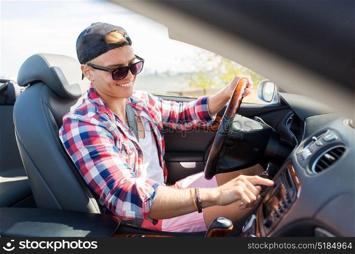 summer holidays, travel, road trip and people concept - happy young man driving convertible car. happy young man driving convertible car