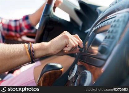 summer holidays, travel, road trip and people concept - young man driving car and turning toggle switch on dashboard. man driving car and turning switch on dashboard