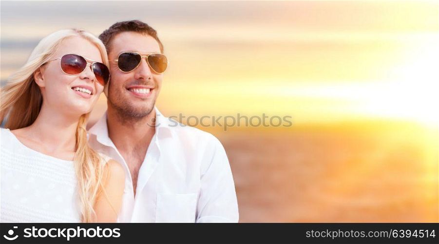 summer holidays, travel, tourism and people concept - happy couple in sunglasses over sea background. happy couple in sunglasses over sea background