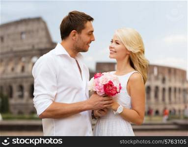 summer holidays, travel, tourism, people and dating concept - happy couple with bunch of flowers over coliseum background