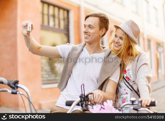 summer holidays, travel, vacation, tourism and dating concept - travelling couple with bicycles taking photo picture with camera