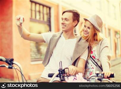 summer holidays, travel, vacation, tourism and dating concept - travelling couple with bicycles taking photo picture with camera