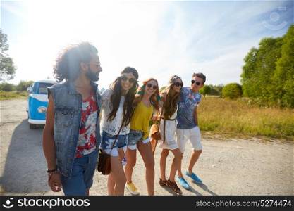 summer holidays, trip, travel and people concept - smiling happy young hippie friends at minivan car walking along road. smiling happy young hippie friends at minivan car