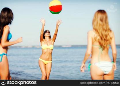 summer holidays, vacation and beach activities concept - girls in bikinies playing ball on the beach