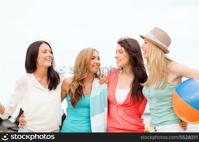 summer holidays, vacation and beach activities concept - smiling girls with ball and towel on the beach