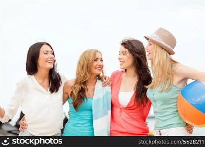 summer holidays, vacation and beach activities concept - smiling girls with ball and towel on the beach
