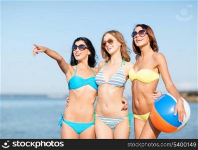 summer holidays, vacation and beach activities - girls in bikinis with ball on the beach