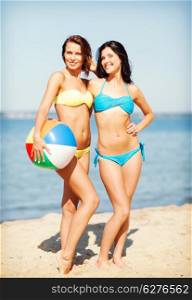 summer holidays, vacation and beach activities - girls in bikinis with ball on the beach