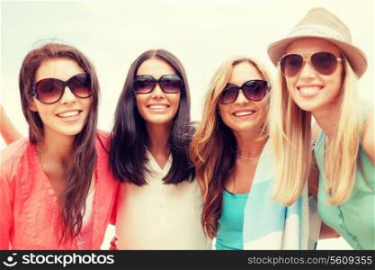 summer holidays, vacation and beach activities - girls in shades having fun on the beach