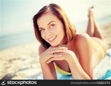 summer holidays, vacation and beach concept - girl sunbathing on the beach