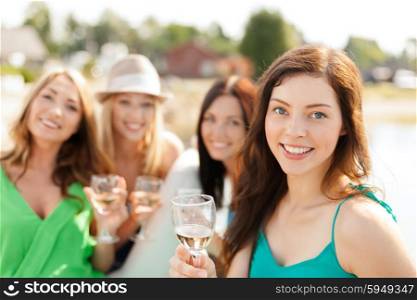summer holidays, vacation and celebration concept - smiling girls with champagne glasses