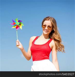 summer holidays, vacation and ecology concept - girl with windmill toy on the beach