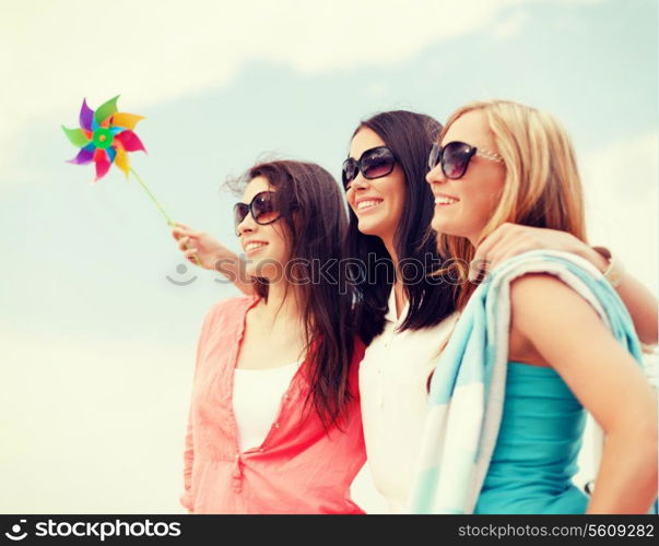 summer holidays, vacation and ecology concept - girls with windmill toy on the beach