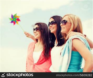 summer holidays, vacation and ecology concept - girls with windmill toy on the beach